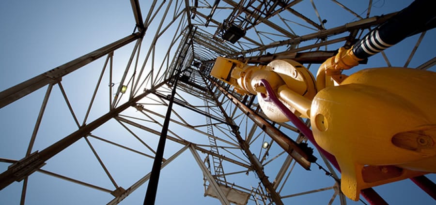 Looking up a drilling rig derrick against a clear West Texas sky
